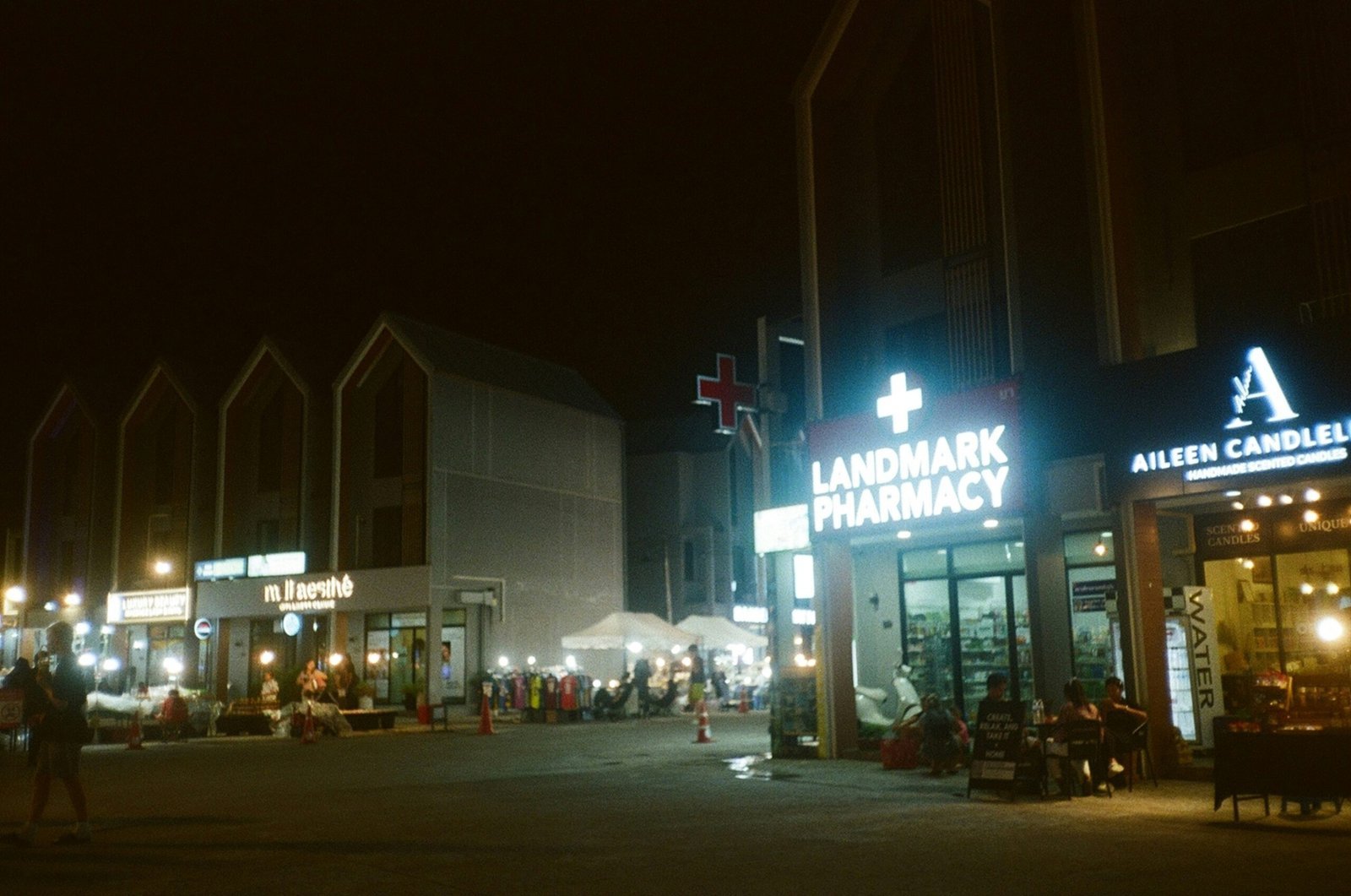 Busy street scene at night with illuminated shops.