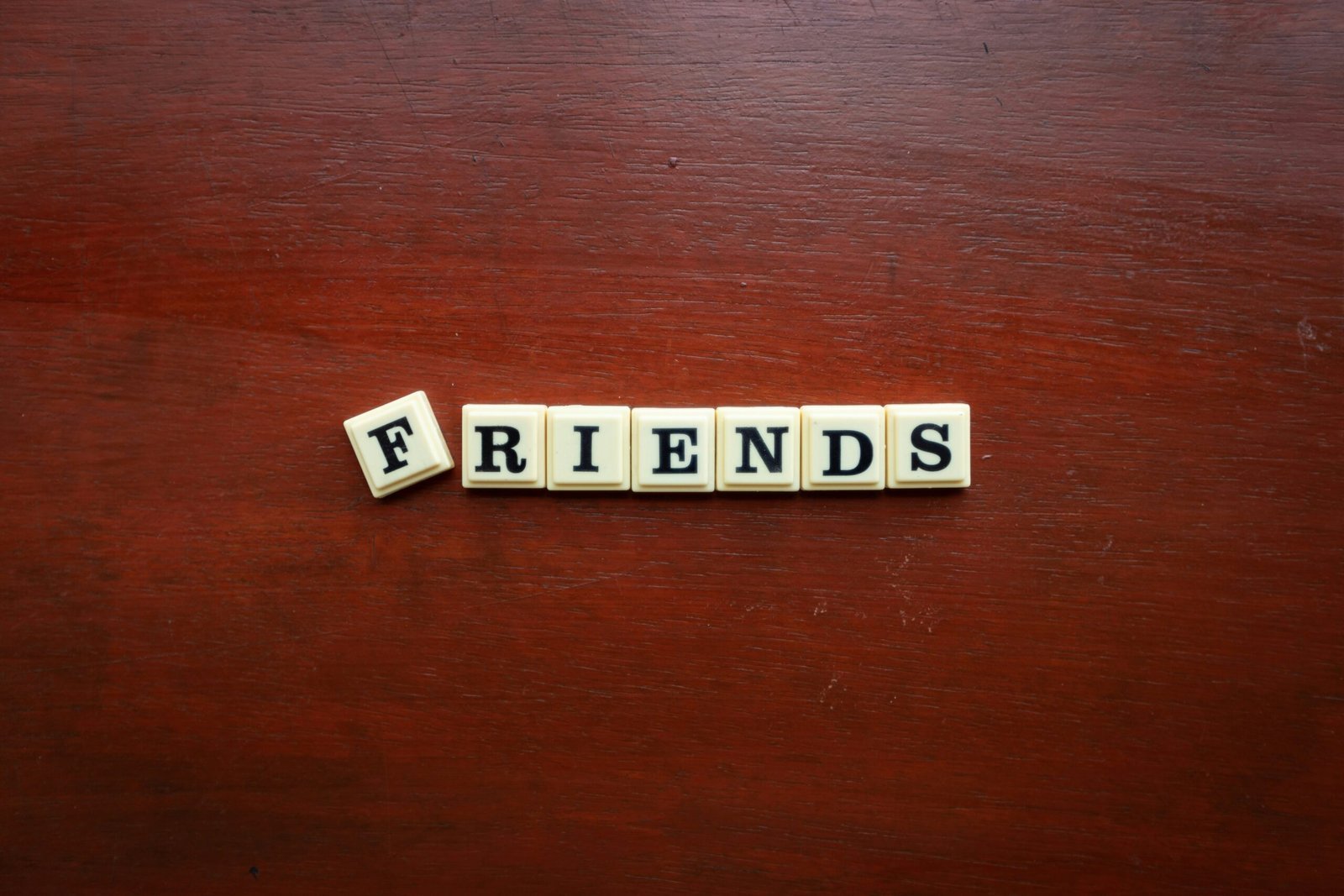 the word friends spelled with scrabbles on a wooden surface